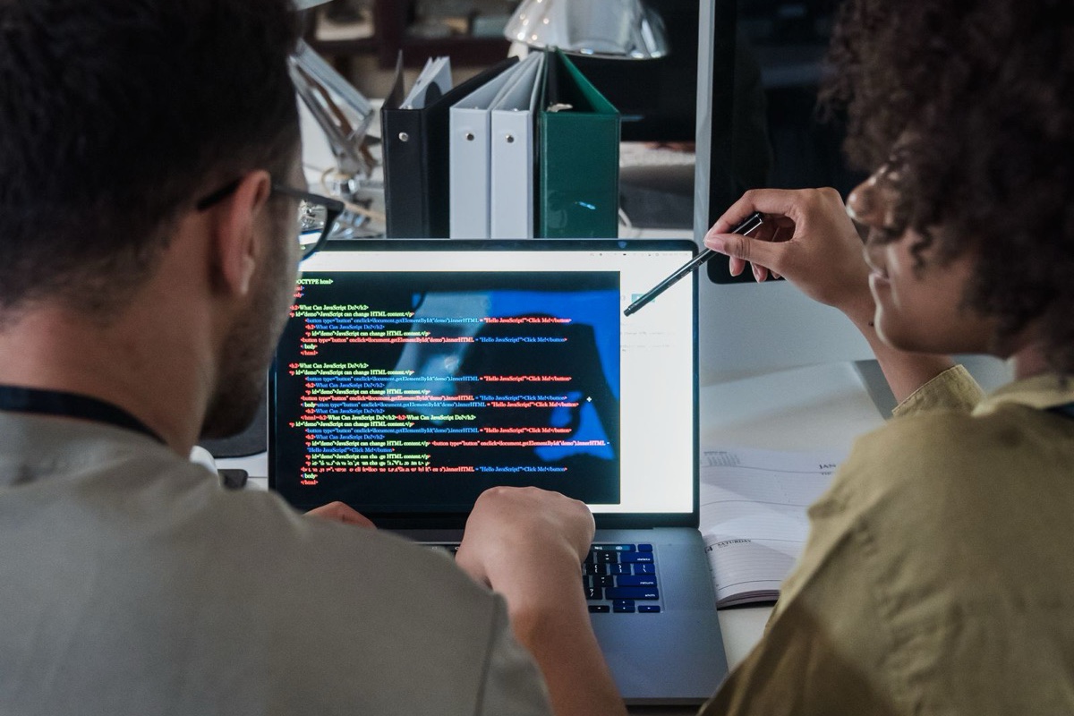 Two developers reviewing code together on a laptop